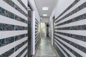 A hallway with tiled walls and a marble floor, leading to a staircase.