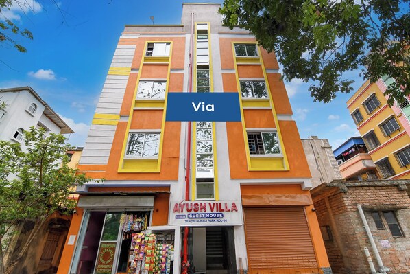 A multi-story building with a sign for 'AYUSH VILLA' indicating a guest house.