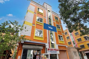 A multi-story building with a sign for 'Ayush Villa' indicating a guest house.