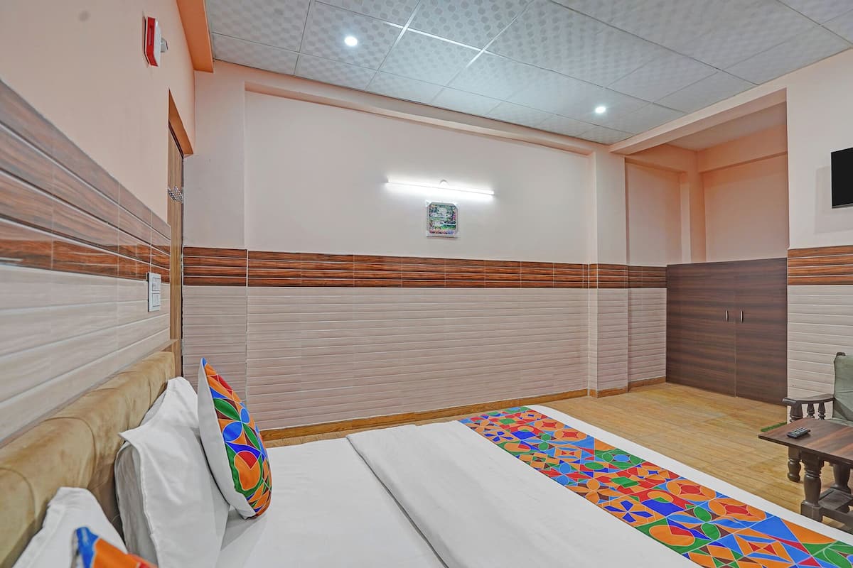 Una habitación de hotel con una cama, un armario de madera, una mesita pequeña y una alfombra colorida.