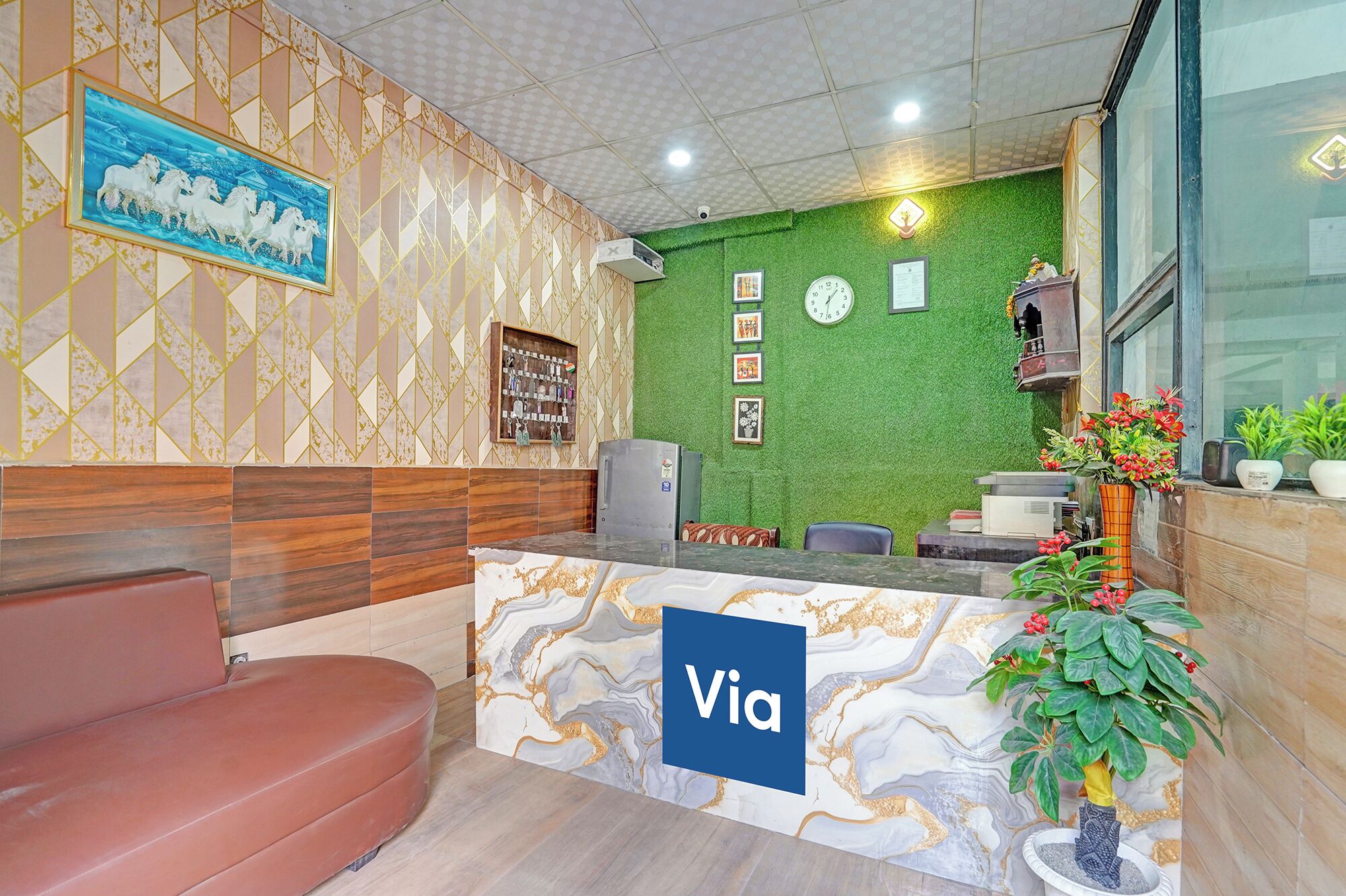 A reception area with a marble counter, a clock, framed pictures, and a green wall.
