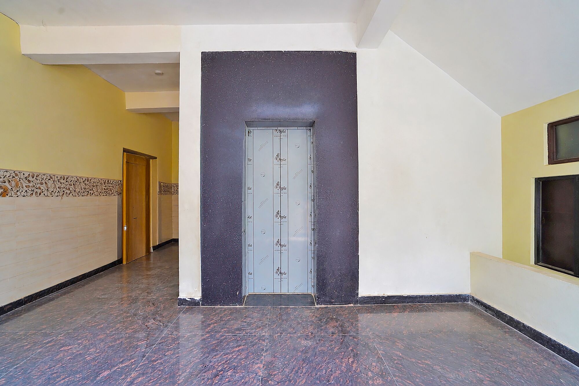 A hallway with a door, tiled walls, and a marble floor.