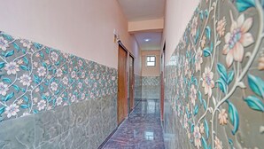 A hallway with floral wall tiles, a marble floor, and a door at the end. - Via Balram - Metro Station Sector 34 Noida (Noida)