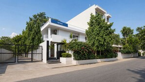 Ein modernes, zweistöckiges Gebäude mit weißer Fassade, einem blauen Schild auf dem Dach und einem befestigten Eingangsbereich.