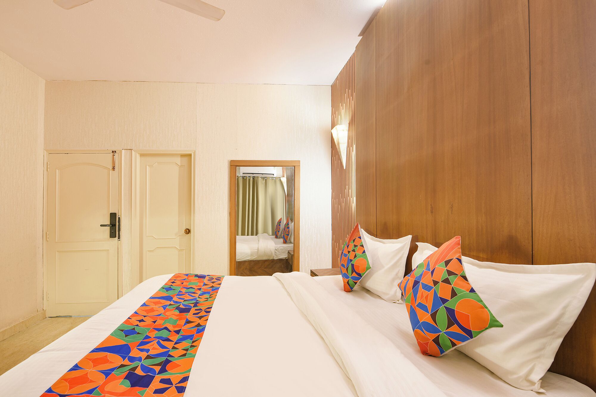 Een hotelkamer met een bed, een spiegel en een wand van houten panelen.