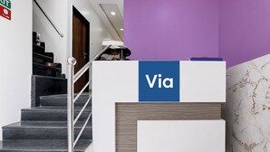 En receptionsdisk med et 'Via' skilt, en trappe med gelændinger i metal og en lilla væg.