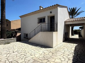 Ein Gebäude mit einem Ziegeldach, einer Treppe, die zu einem Balkon führt, und einem mit Steinplatten befestigten Innenhof.