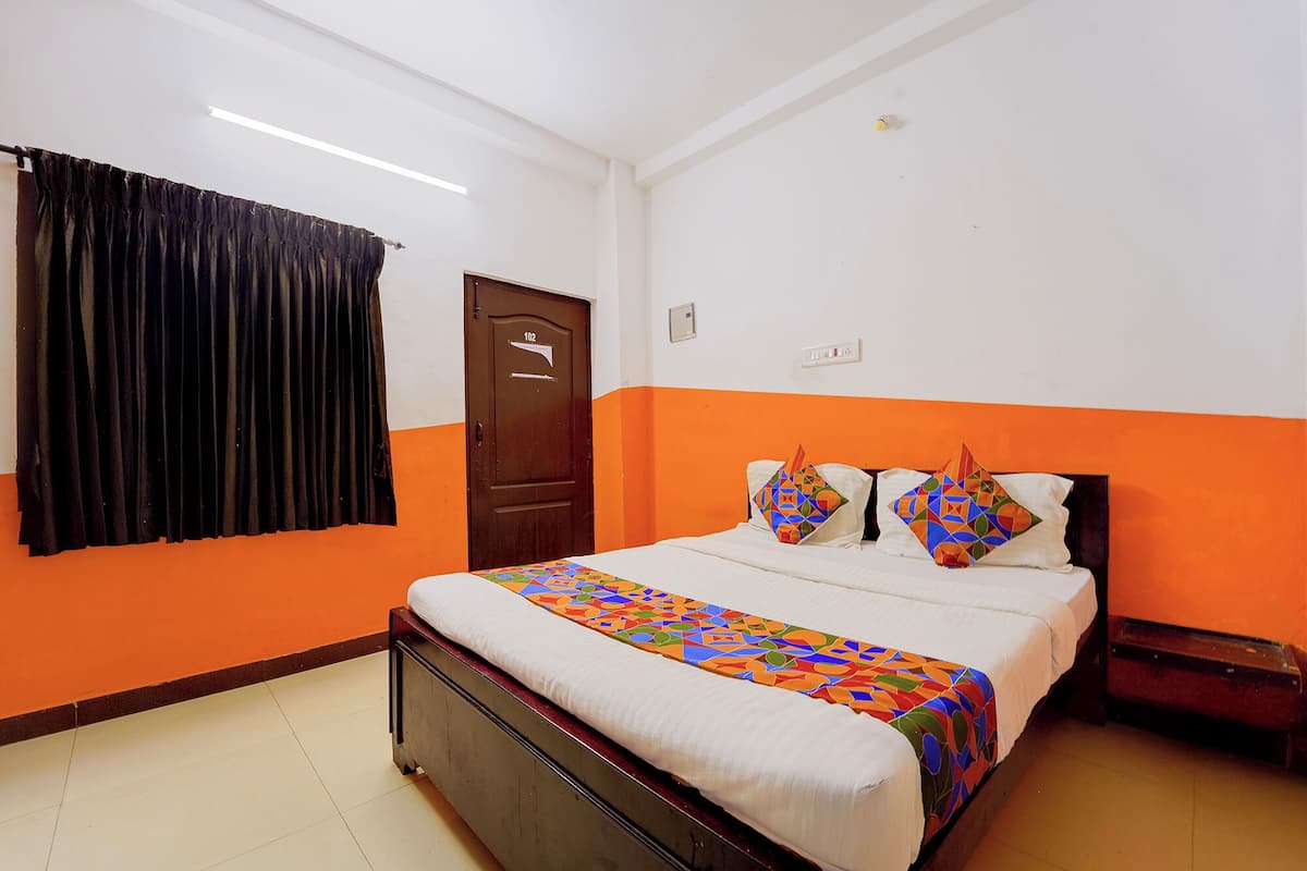 A room with a bed, a door, and a window with curtains.