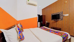 A hotel room with a bed, a TV mounted on a wooden wall, and an air conditioning unit on the wall. - Via Zane - Nr Coimbatore International Airport (Coimbatore)