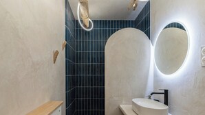 A modern bathroom with a white sink, a mirror, and a shower area with blue tiles. - Newly studio apartment in a quiet residence (Mandelieu-la-Napoule)