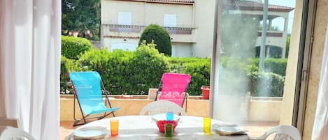 A table set for two with a tablecloth, two chairs, and a vase with flowers.