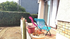 Kaktee, zwei Stühle und Topfpflanzen auf einer Terrasse.