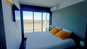 Ein Schlafzimmer mit Bett, Blick ins Freie und einer wandmontierten Klimaanlage.