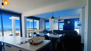 A modern kitchen with a large island, dining area with tables and chairs, and large windows offering a view of the sea. - apartment with terrace in Saint-Cyprien (Saint-Cyprien)