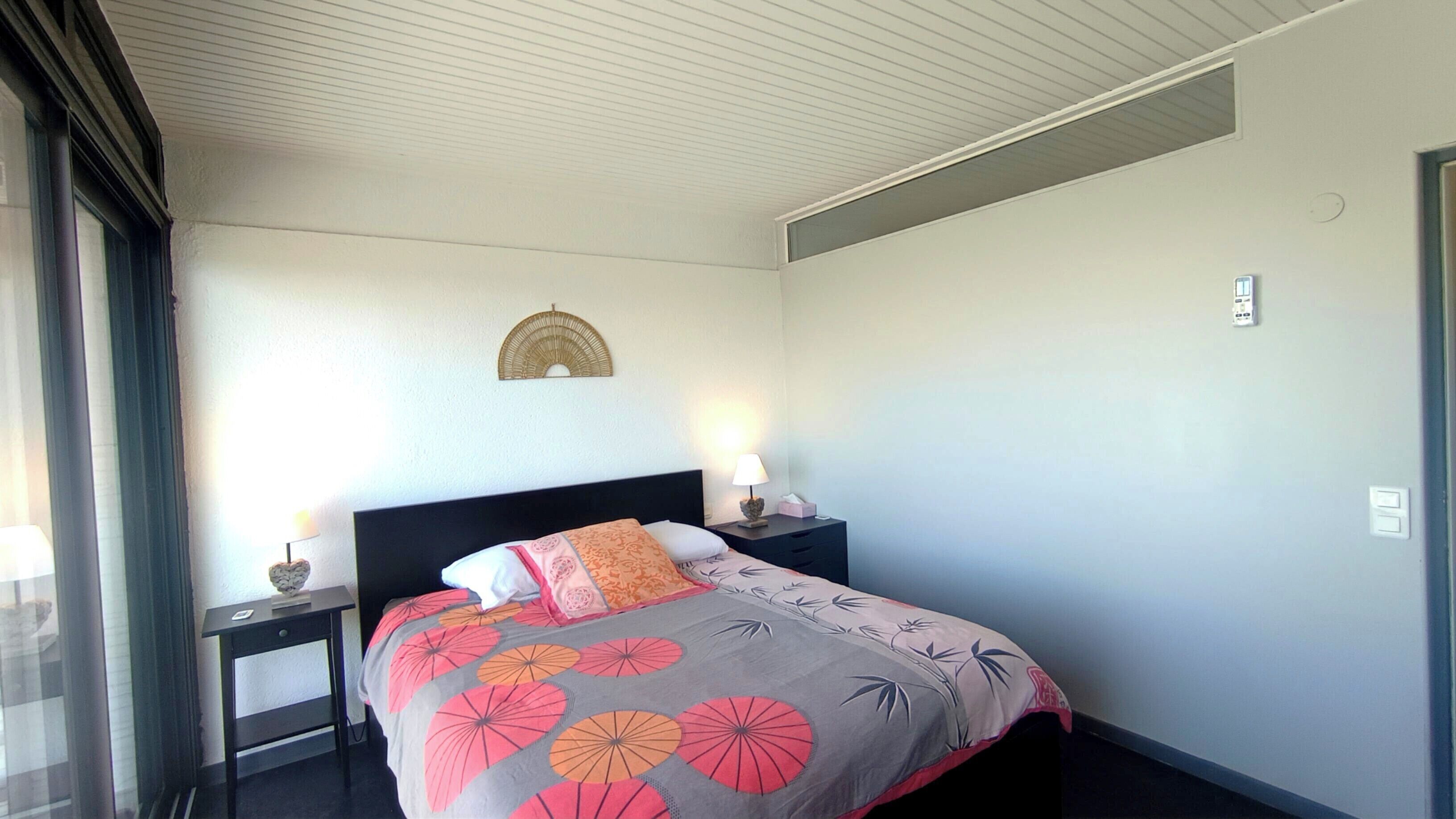 Een hotelkamer met een bed, twee nachtkastjes met lampen, een wandlamp en een raam met gordijnen.