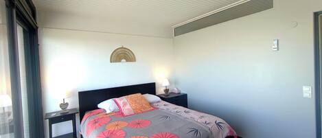 Een hotelkamer met een bed, twee nachtkastjes met lampen, een wandlamp en een raam met gordijnen.