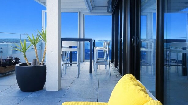 A balcony with a yellow cushion, potted plants, and a view of the sea. - apartment with terrace in Saint-Cyprien (Saint-Cyprien)