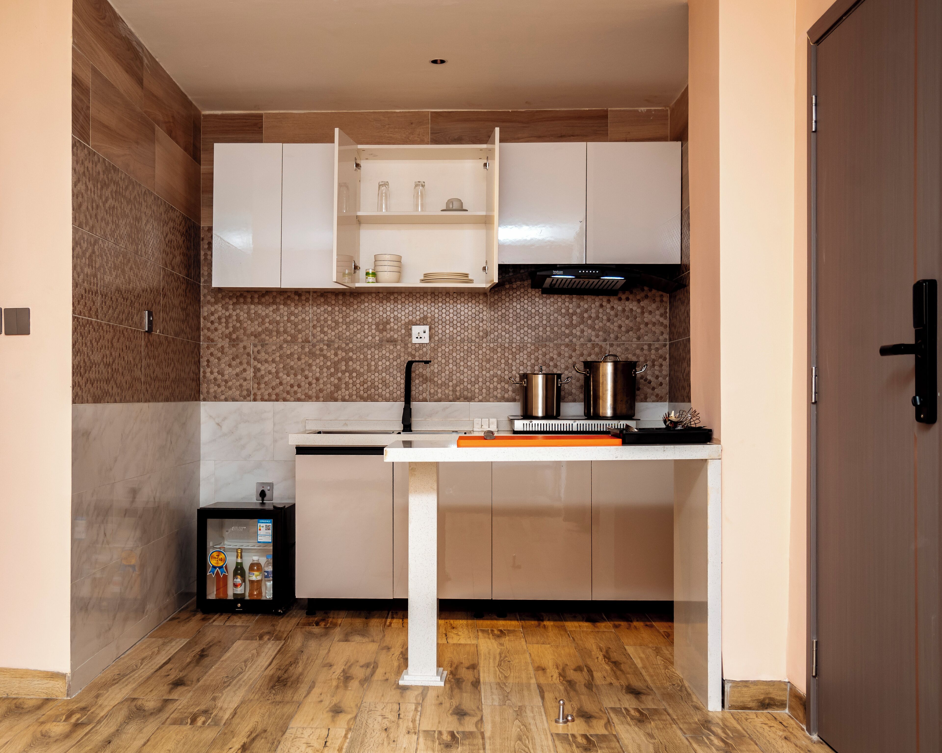 A compact kitchen with white cabinets, a wooden backsplash, and a built-in oven.