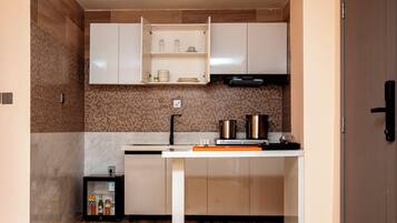 A compact kitchen with white cabinets, a wooden backsplash, and a built-in oven.