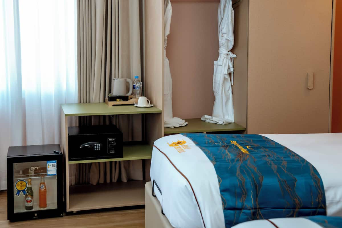 A hotel room with a bed, a desk with a coffee maker, a microwave, and a minibar.