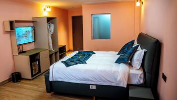 A bedroom with a bed, a TV, a robe, and a wardrobe.