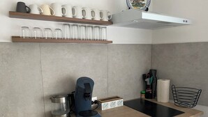 A modern kitchen with a coffee maker, a kettle, and a tablet on the counter.