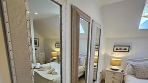 A bedroom with a large mirror, a bed, a nightstand, and a dresser.