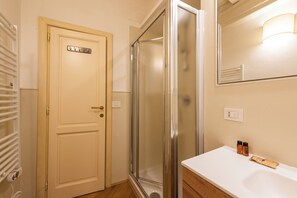 Ein Badezimmer mit Dusche, Waschbecken, Spiegel und Tür.
