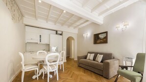 Ein Essbereich mit weißen Stühlen und einem Tisch, einer Couch und einem Gemälde an der Wand.