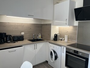 A compact kitchen with a washing machine, dishwasher, and a built-in oven. - Cesaree Residence – Renovated 2-room apartment with pool view, air conditioning, garage and terrace – Sleeps 4. (Fréjus)