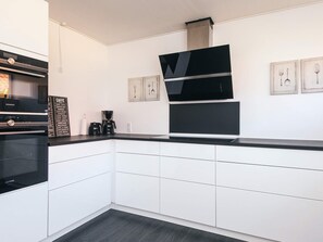 A modern kitchen with white cabinetry, a black countertop, and a Siemens oven. - 8 Person Holiday Home in Hadsund (Hadsund)