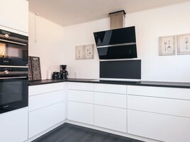 A modern kitchen with white cabinetry, a black countertop, and a Siemens oven.