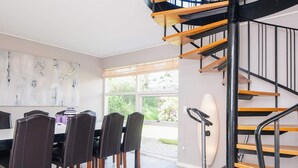 Un comedor moderno con escalera de madera y vista al exterior.