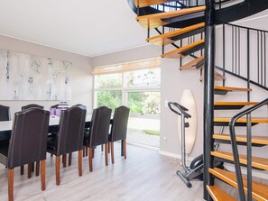 A modern dining area with a wooden staircase and a view of the outdoors. - 8 Person Holiday Home in Hadsund (Hadsund)
