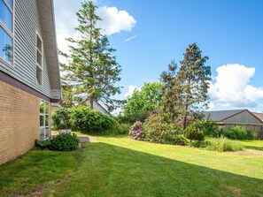 A residential backyard with a lawn, a tall tree, and a brick house. - 8 Person Holiday Home in Hadsund (Hadsund)