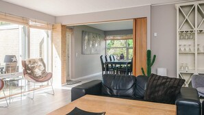 Una sala de estar moderna con una mesa de comedor de madera, un sofá de cuero negro y una planta de cactus.