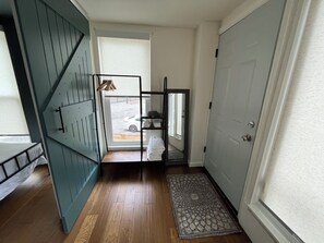 Un passadís amb sòl de fusta, una porta, una finestra amb vista a un cotxe a l'exterior i una petita catifa.