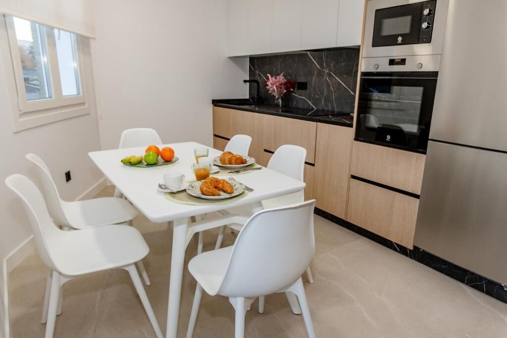 A modern kitchen with white cabinetry, a marble countertop, and stainless steel appliances.