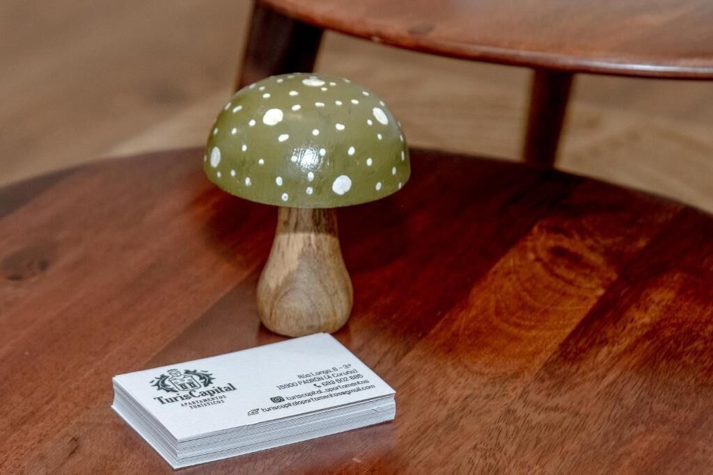 Una mesa de madera con una tarjeta de presentación blanca y un objeto en forma de hongo verde.