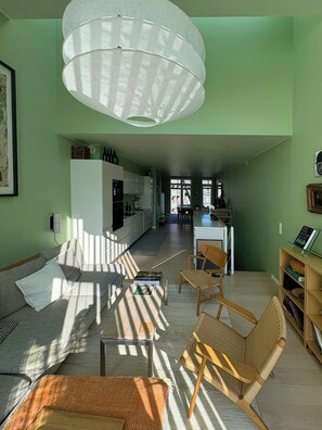A modern living room with a sofa, chairs, a coffee table, and a kitchen in the background.