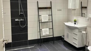 Une salle de bain moderne équipée d’une douche, d’un porte-serviettes, d’un lavabo et d’un miroir.