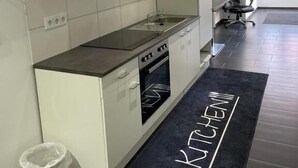 Une cuisine moderne avec des meubles blancs, un plan de travail noir et un tapis noir sur lequel est écrit le mot « CUISINE ».