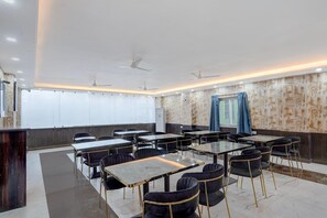 A conference room with tables and chairs, ceiling fans, and a patterned wall.
