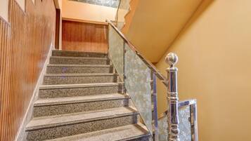 A staircase with granite steps, a wooden wall on one side, and a metal railing with a floral pattern on the other.