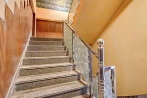 A staircase with granite steps, a wooden wall on one side, and a metal railing with a floral pattern on the other.