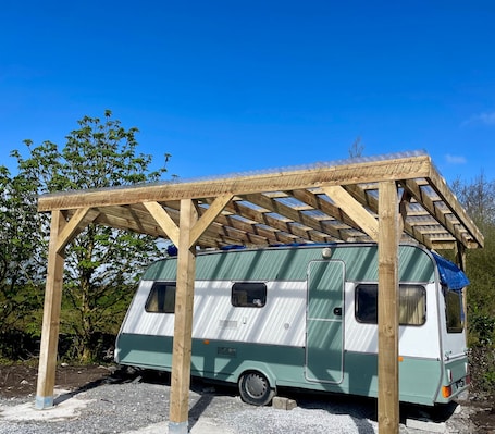 A campervan under a wooden pergola structure.