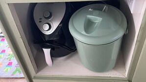 Una cocina con cafetera, hervidor y una olla verde.