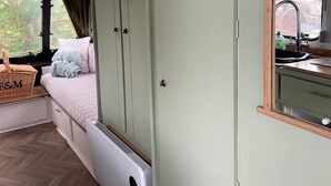 Habitación compacta con cama, armario, una ventana pequeña y baño visible a través de la puerta.