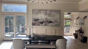 A dining area with a table, chairs, and a painting on the wall.