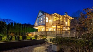 A two-story house with a balcony, a covered porch, and a well-lit exterior.